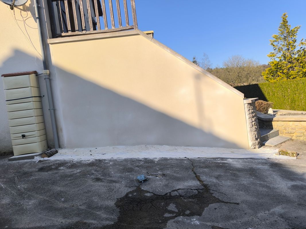 Enduit taloché clair appliqué sur un mur extérieur en pente