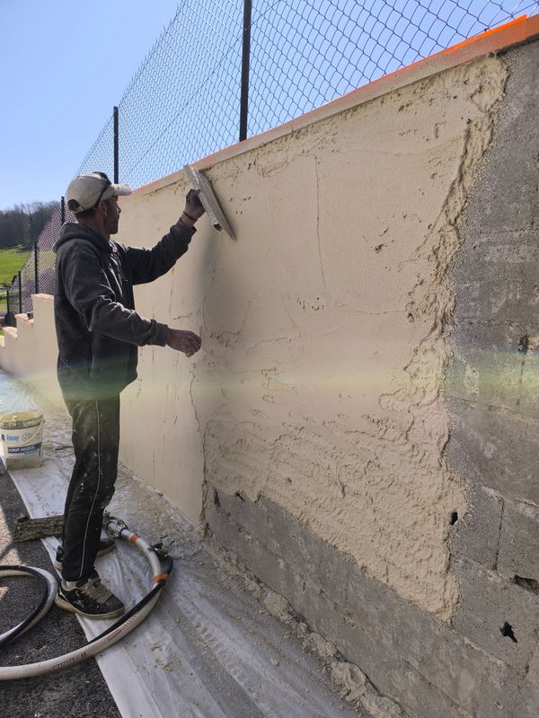 Artisan appliquant un enduit taloché à la truelle sur un mur